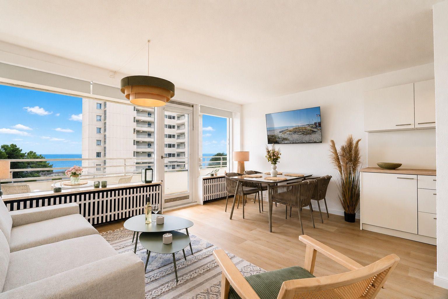 Living area with dining space, balcony, and sea view. Modern furnishings and bright ambiance.