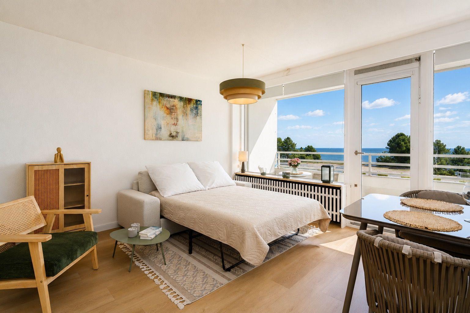 A bedroom with sea view, furniture and wall art are visible.