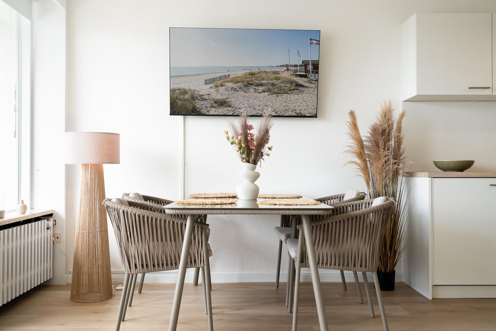 Dining area with table, chairs, and TV mounted on the wall.