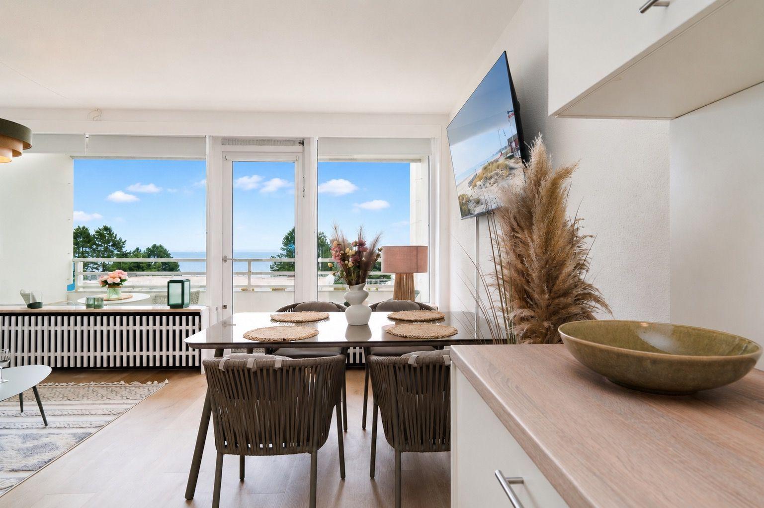 Dining area with table, chairs, and view of the beach.