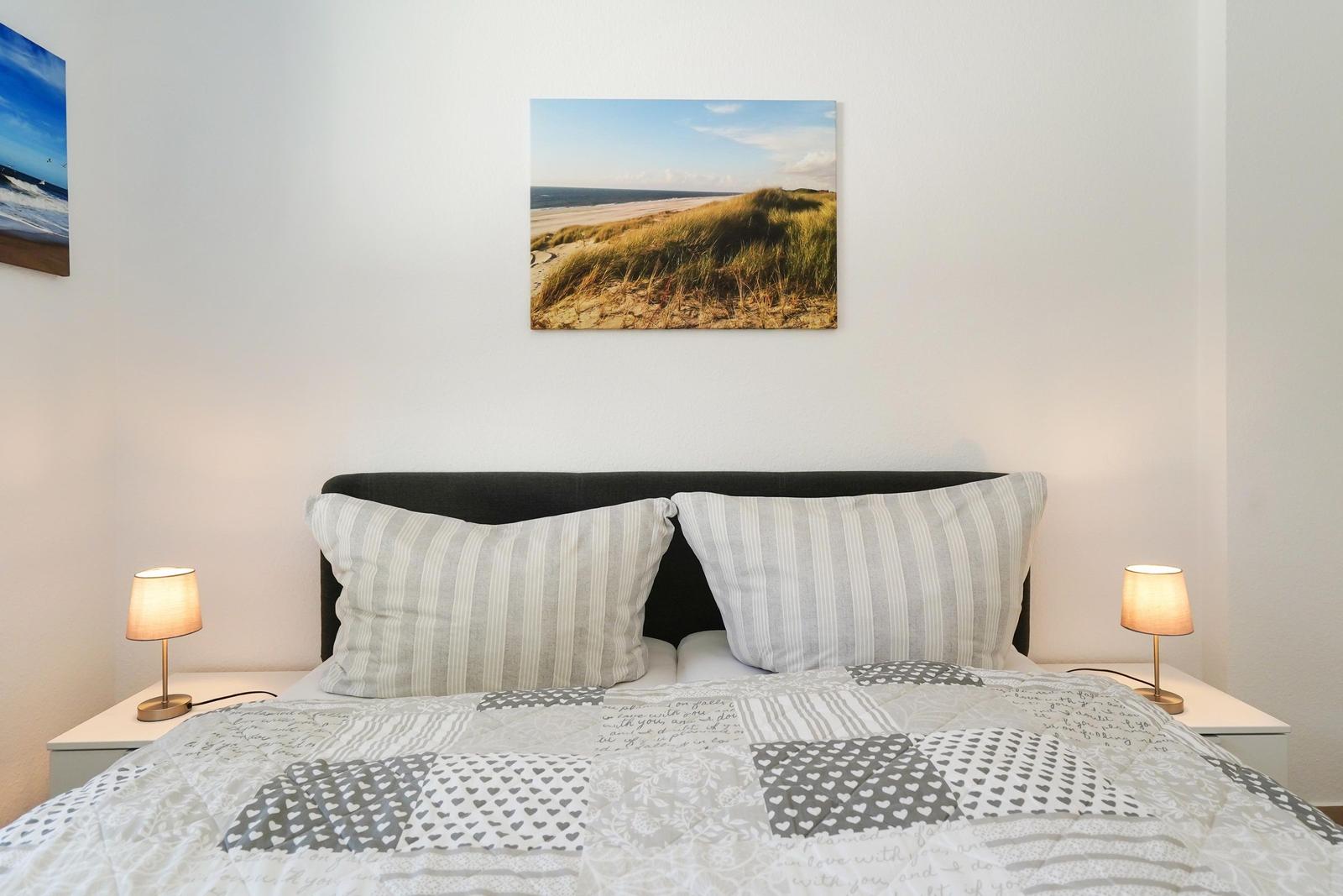 Schlafzimmer mit Bett, zwei Nachttischen und Wandbildern