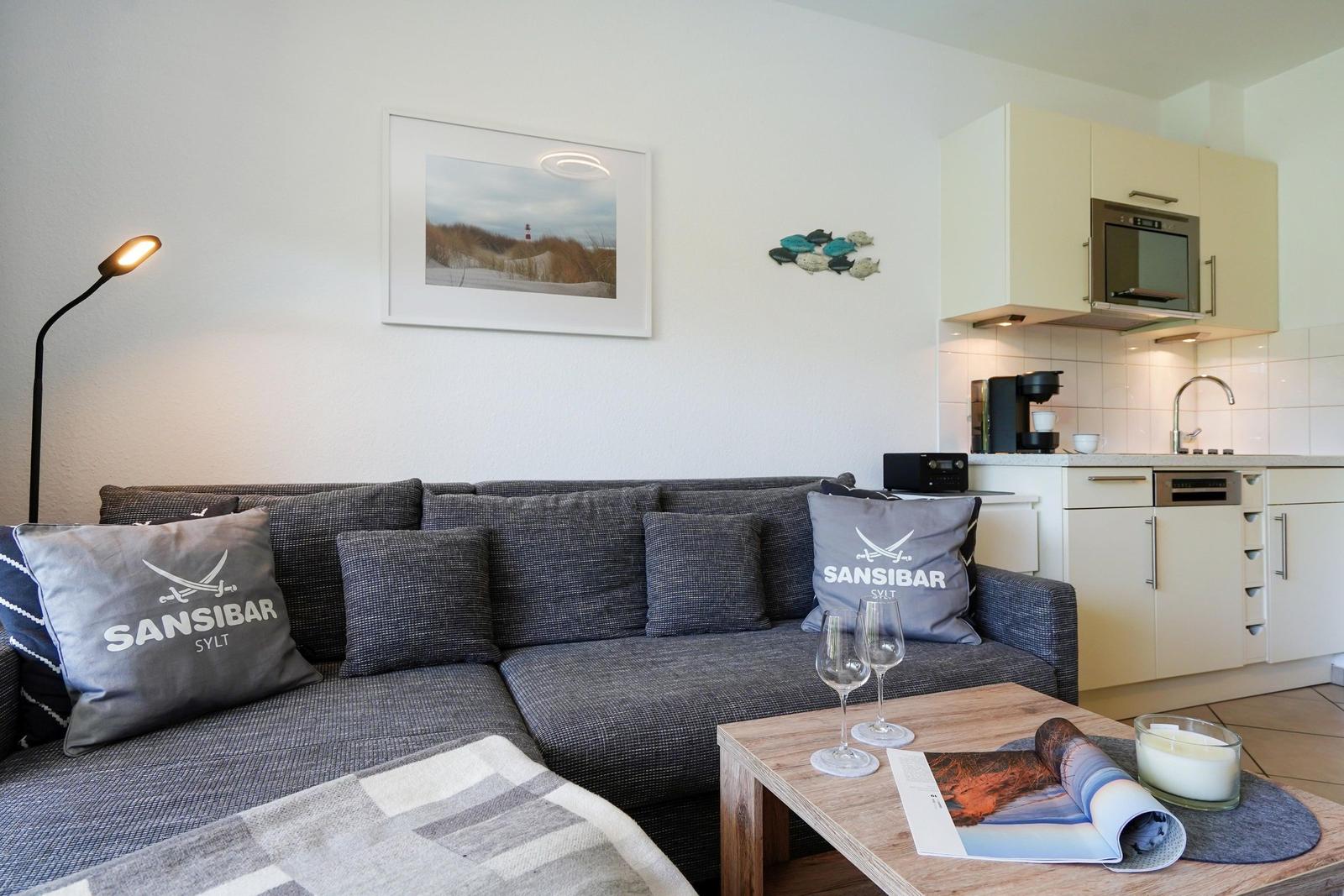 Wohnzimmer mit Sofa, Couchtisch und Küchenbereich im Hintergrund.