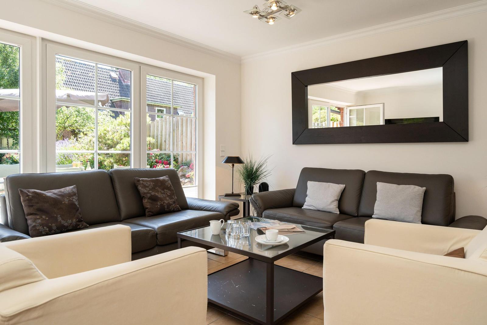 Wohnzimmer mit zwei Sofas, Glas-Tisch und großem Spiegel an der Wand.