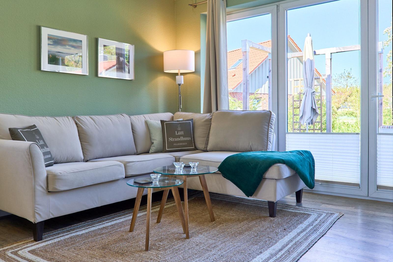 Ein Wohnzimmer mit Sofa, Tisch und Blick auf Balkon.