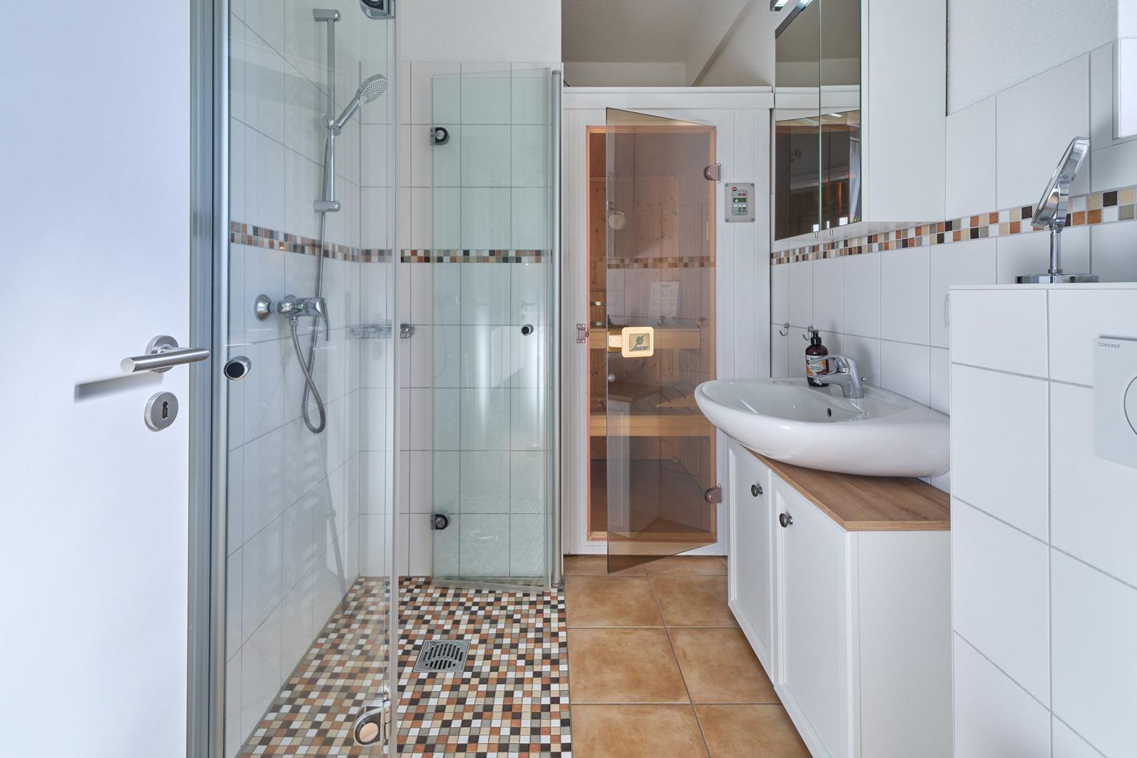 Badezimmer mit Dusche, Waschbecken und Sauna.