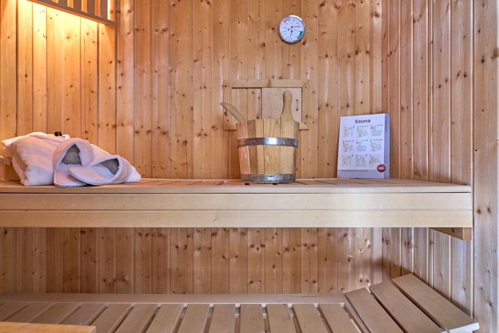 Sauna mit Holzbank, Eimer, Thermometer und Handtuch