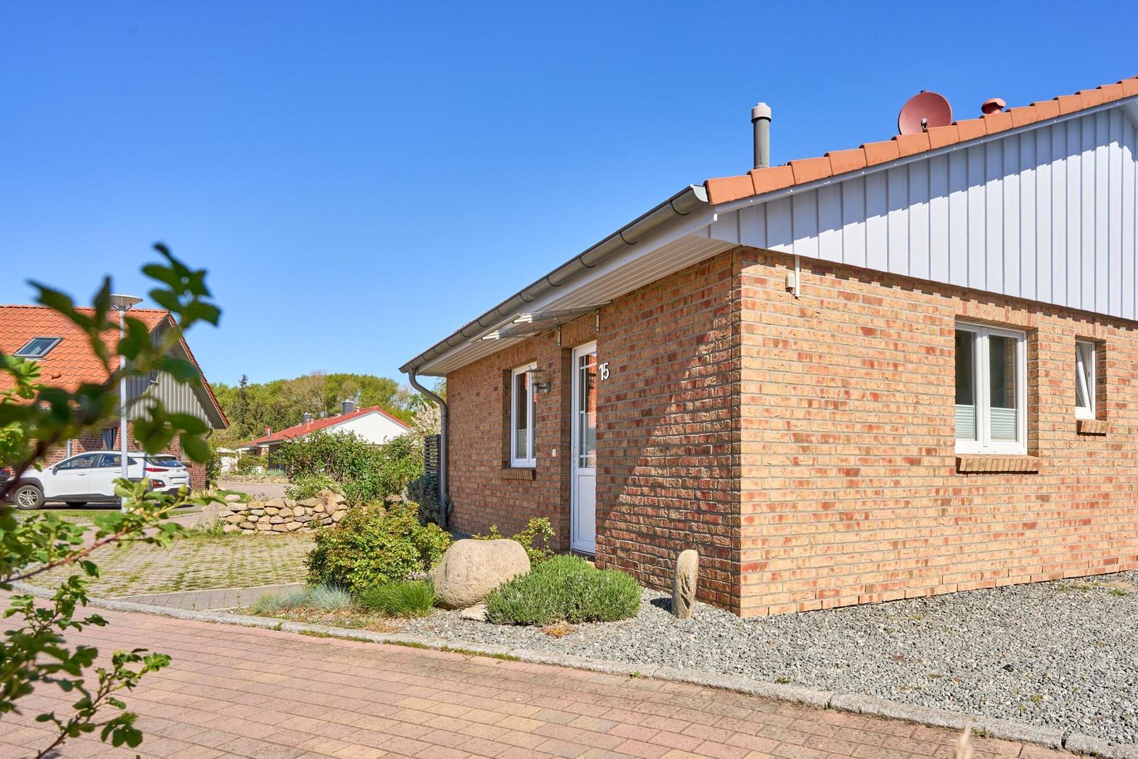 Ein Haus mit Backsteinfassade und weißen Fenstern. Dach mit roten Ziegeln und Satellitenschüssel.