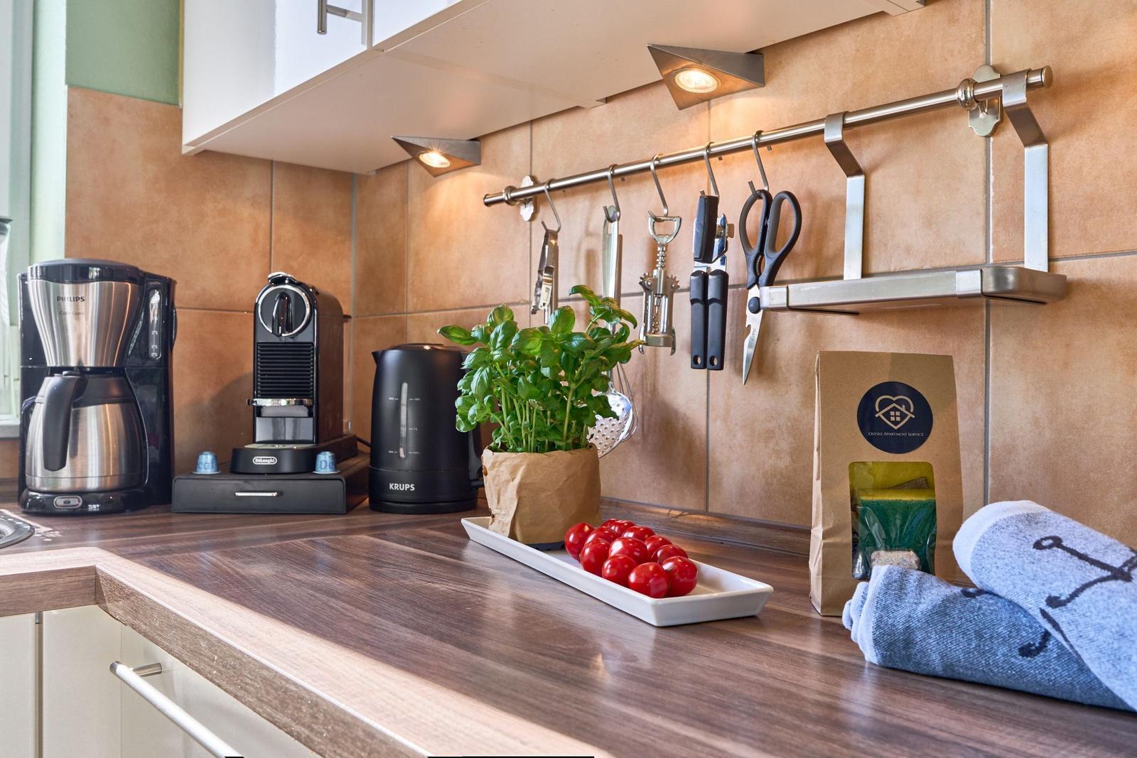 Küchenarbeitsfläche mit Kaffeemaschine, Wasserkocher und frischen Tomaten.