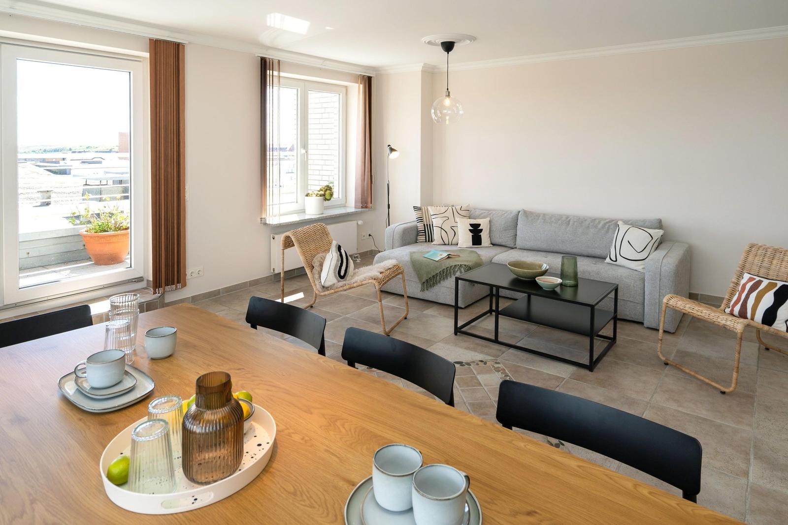 Wohn- und Essbereich mit Sofa, Esstisch und Fenstern mit Blick.