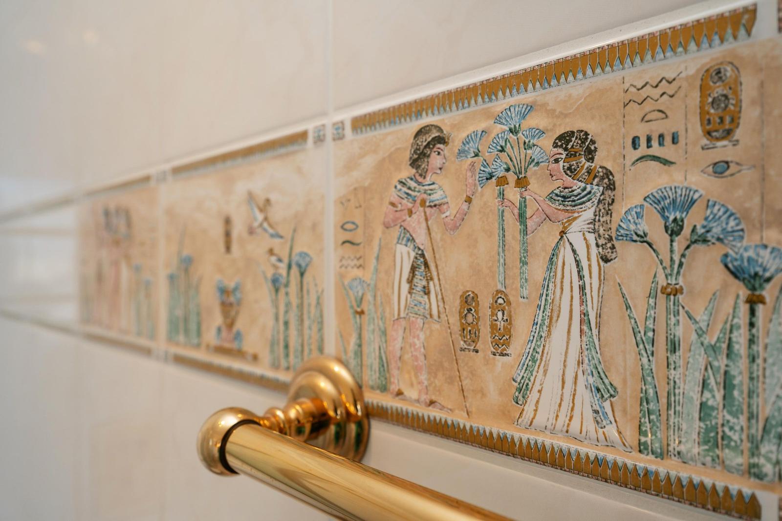 Bad mit ägyptischen Mosaikfliesen und goldener Handtuchstange