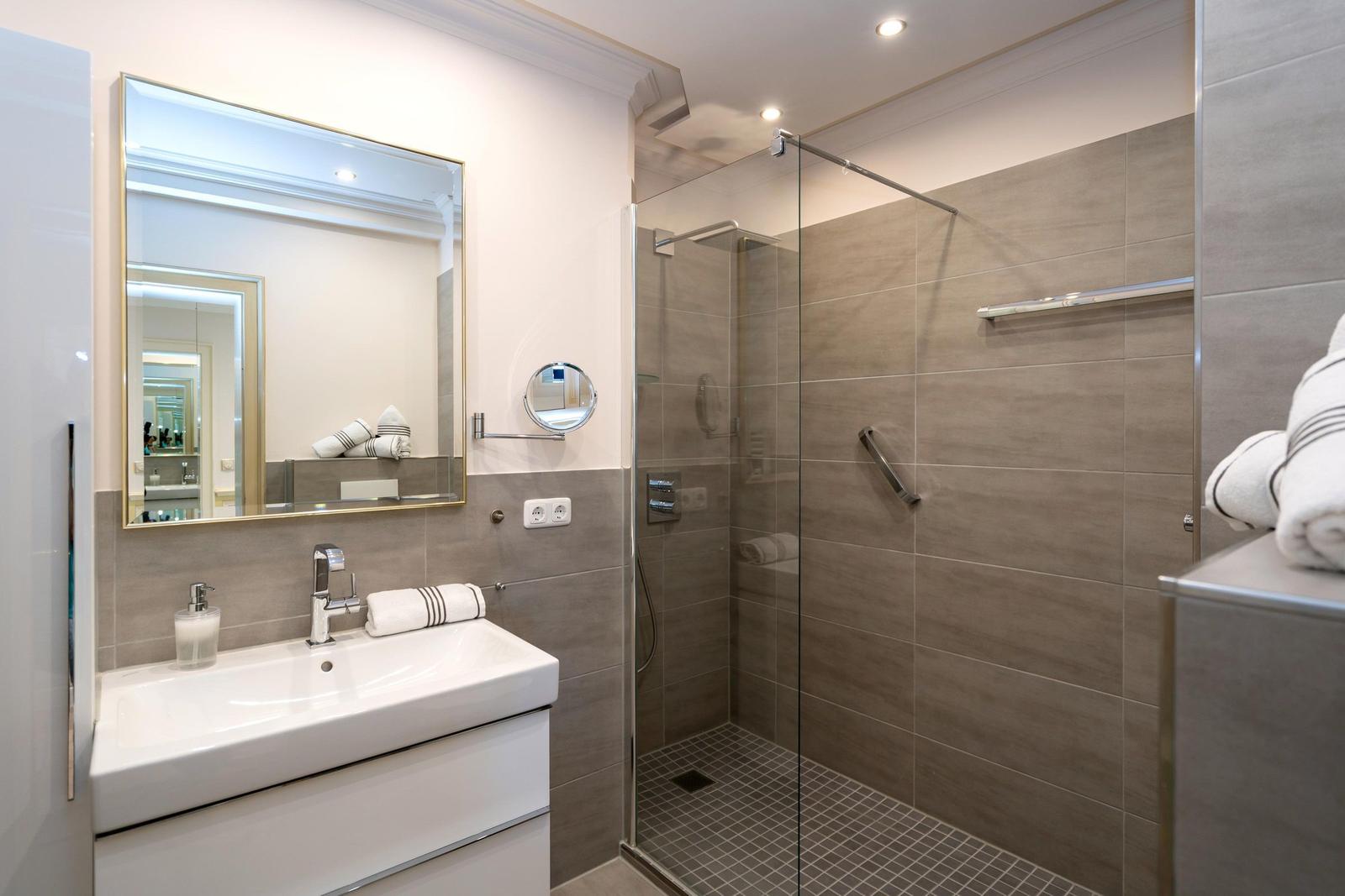 Badezimmer mit Dusche, Waschbecken und Spiegel