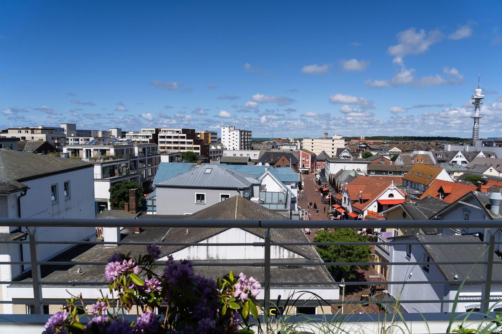Ruhige Aussicht auf Stadt mit Dächern und Turm unter blauem Himmel.