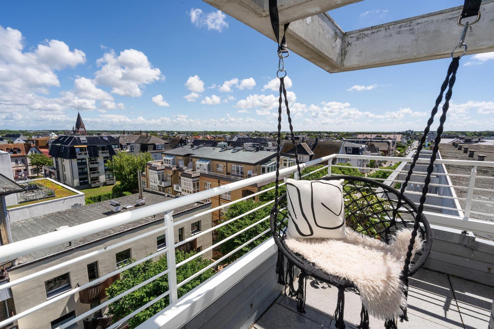Hängesessel auf Terrasse mit Blick auf Stadt und Kirche