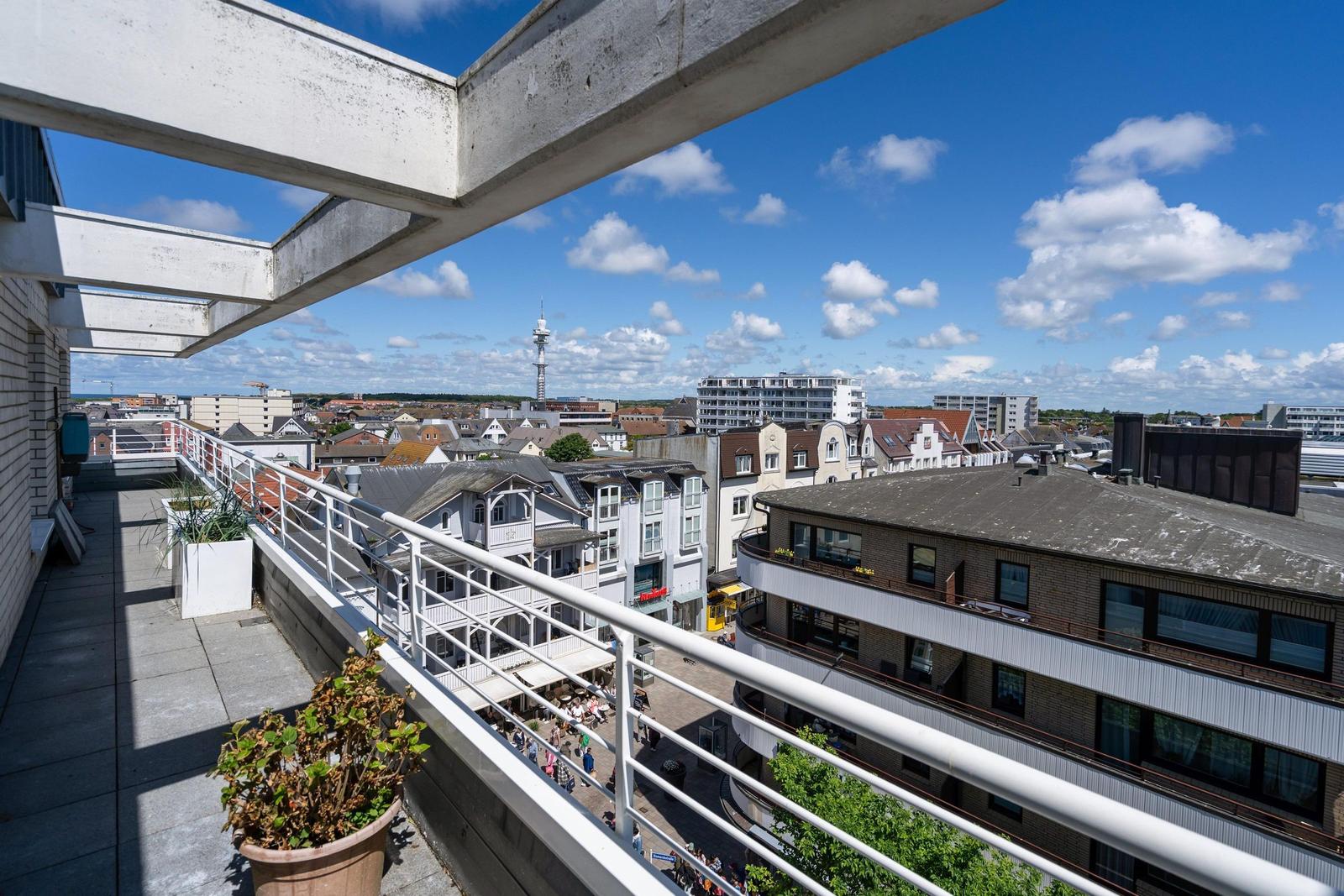 Terrasse mit Blick auf Stadt und Fernsehturm unter blauem Himmel mit weißen Wolken.