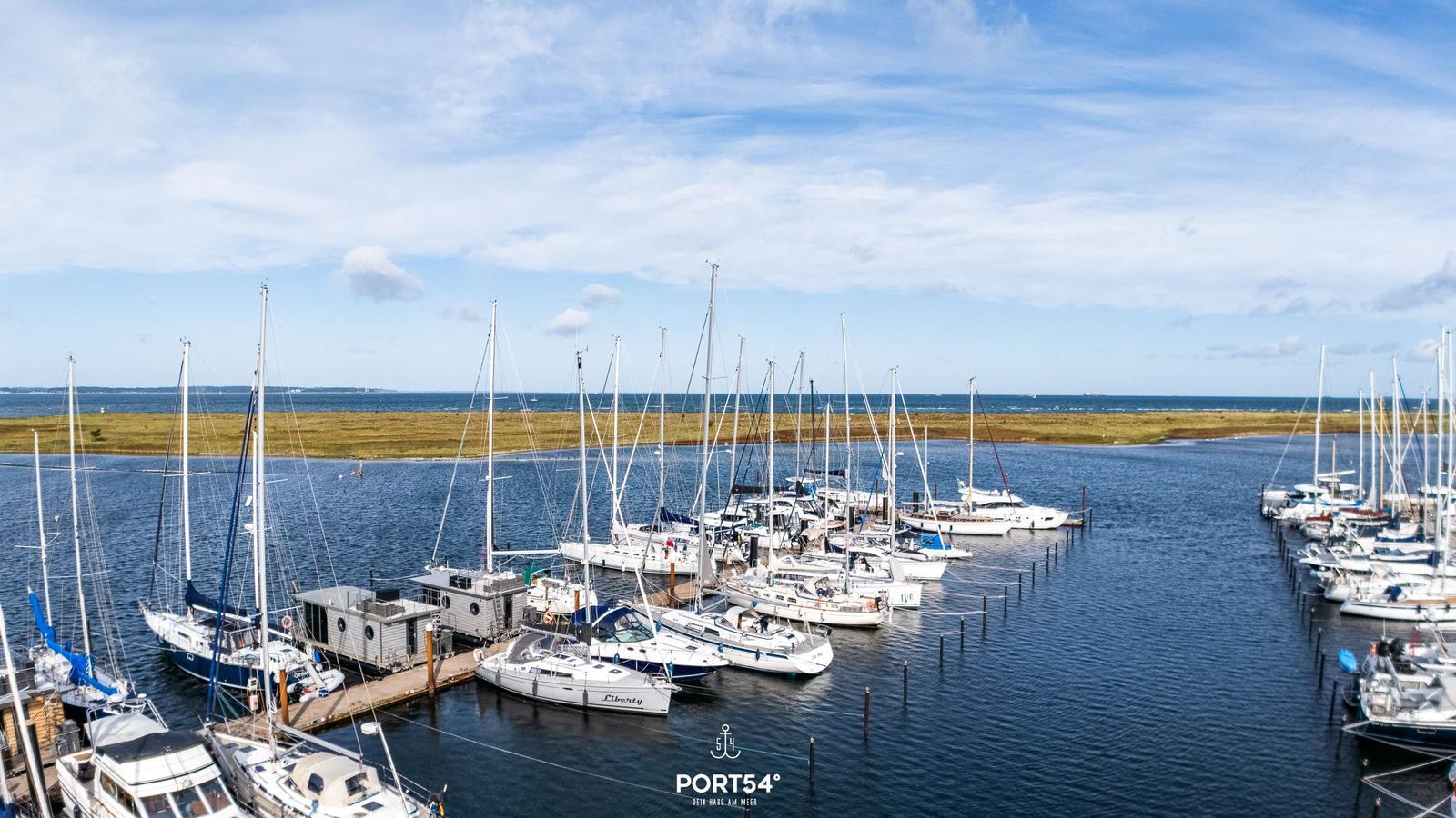 Hafen mit vielen Segelyachten und Booten im Wasser unter blauem Himmel.