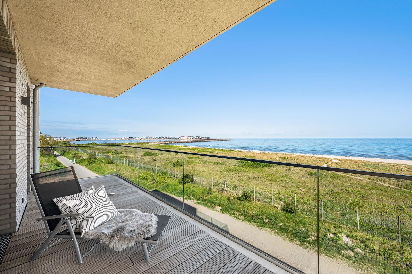 Terrasse mit Liegestuhl und Blick auf das Meer und Strand.