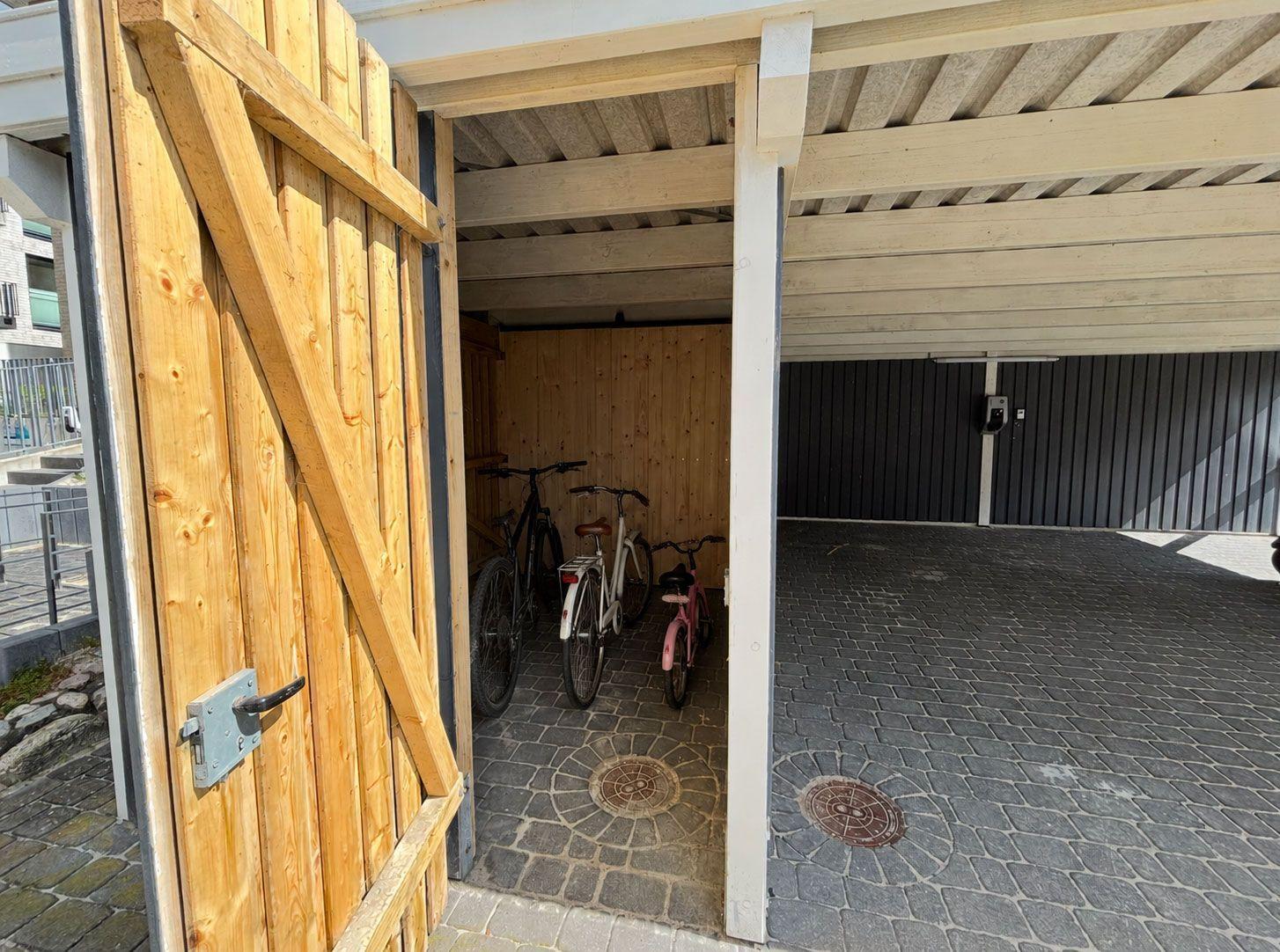 Holztor führt zu Garage mit drei Fahrrädern und gepflastertem Boden.