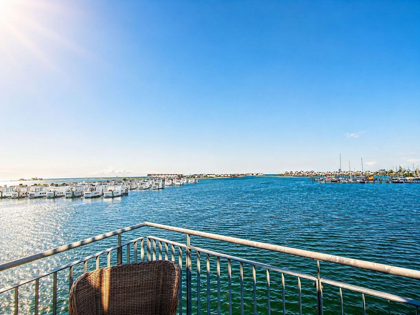 Terrasse mit Stuhl blickt auf Wasser und Bootshäuser