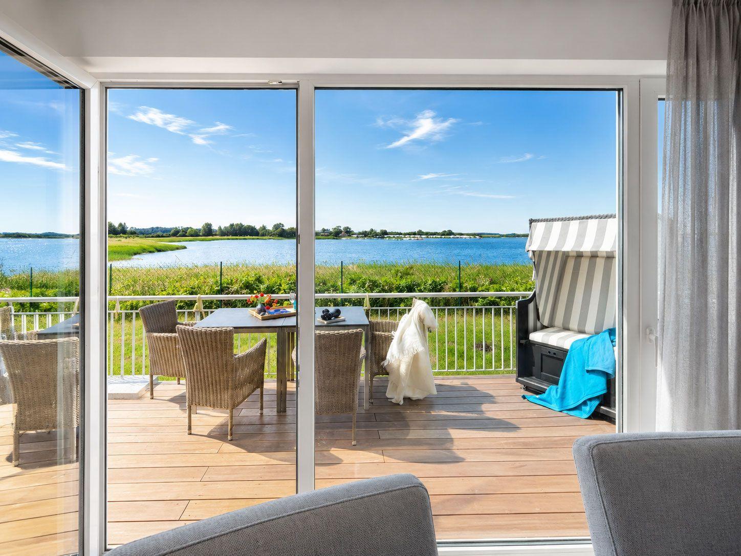 Terrasse mit Tisch, Stühlen und Blick auf einen See.