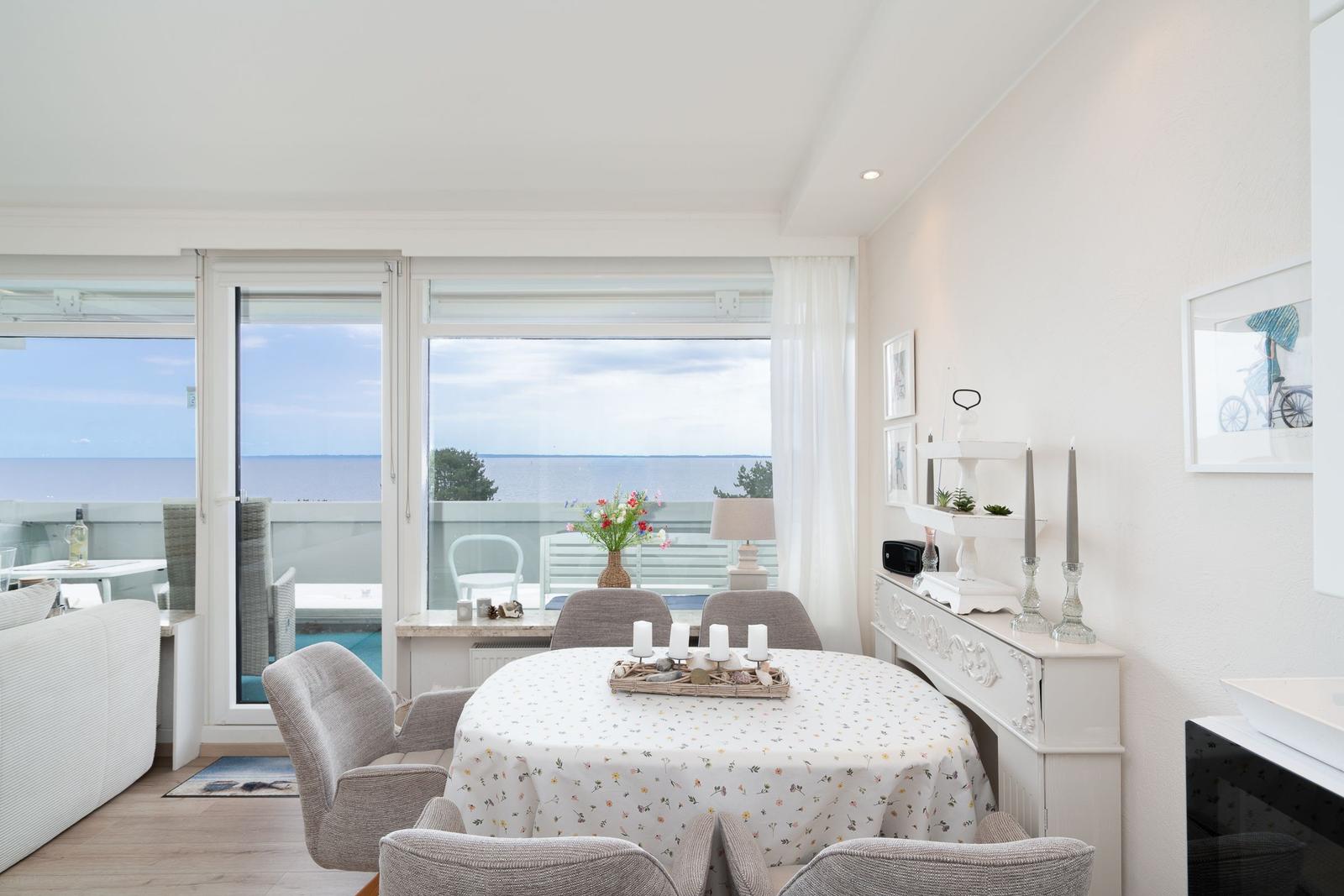 Esszimmer mit Tisch, Stühlen und Meerblick durch große Fenster.