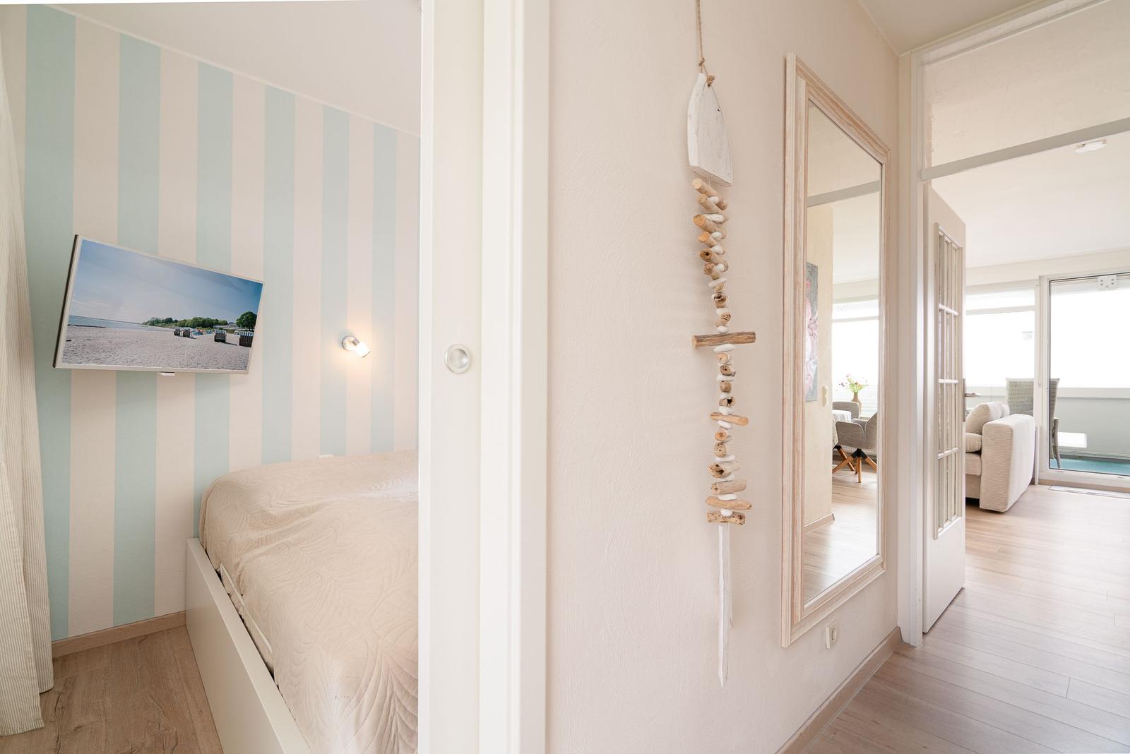 Schlafzimmer mit Bett und Wandbild. Flur mit Spiegel und Seehandwerk.