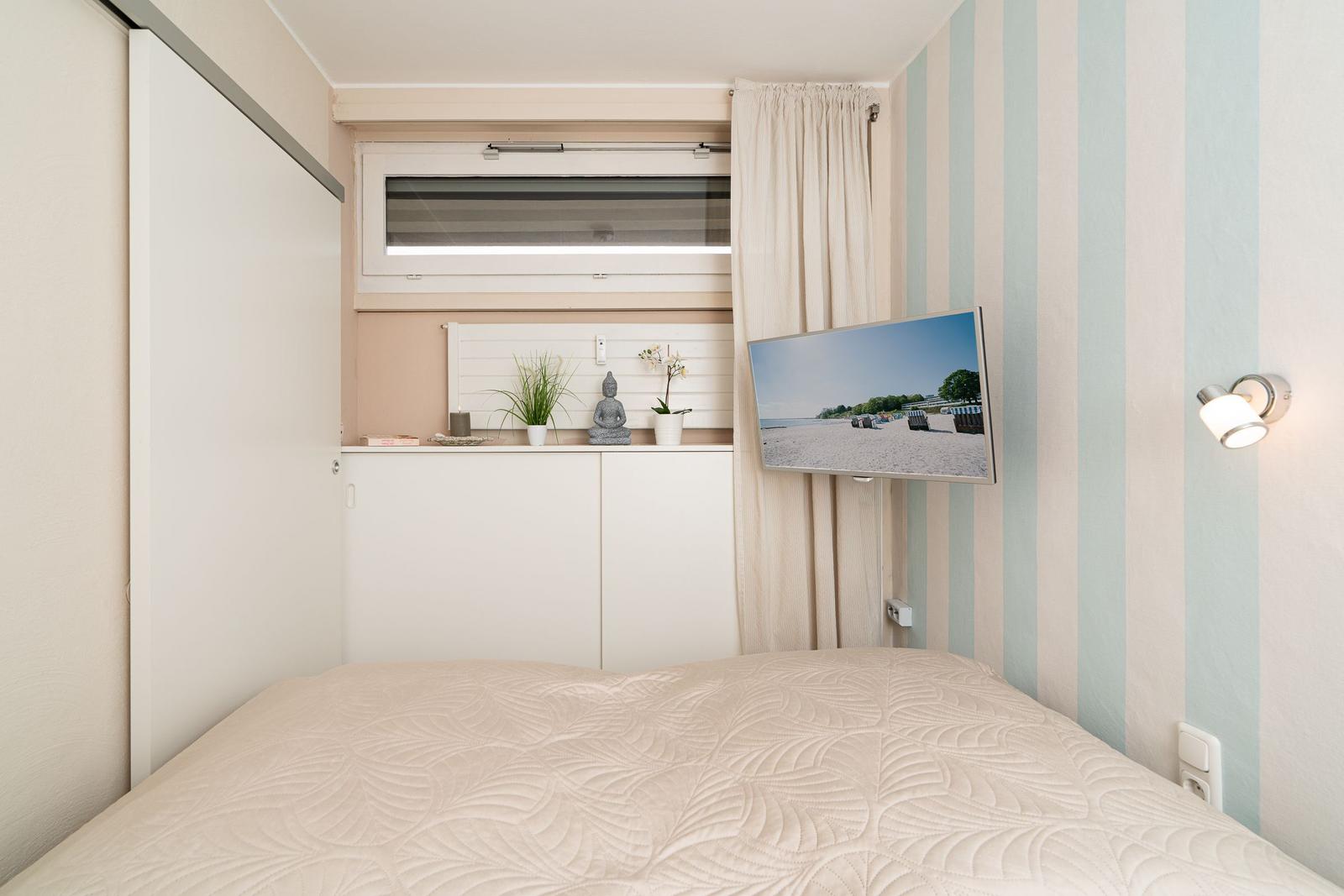Schlafzimmer mit Bett, TV und Fenster