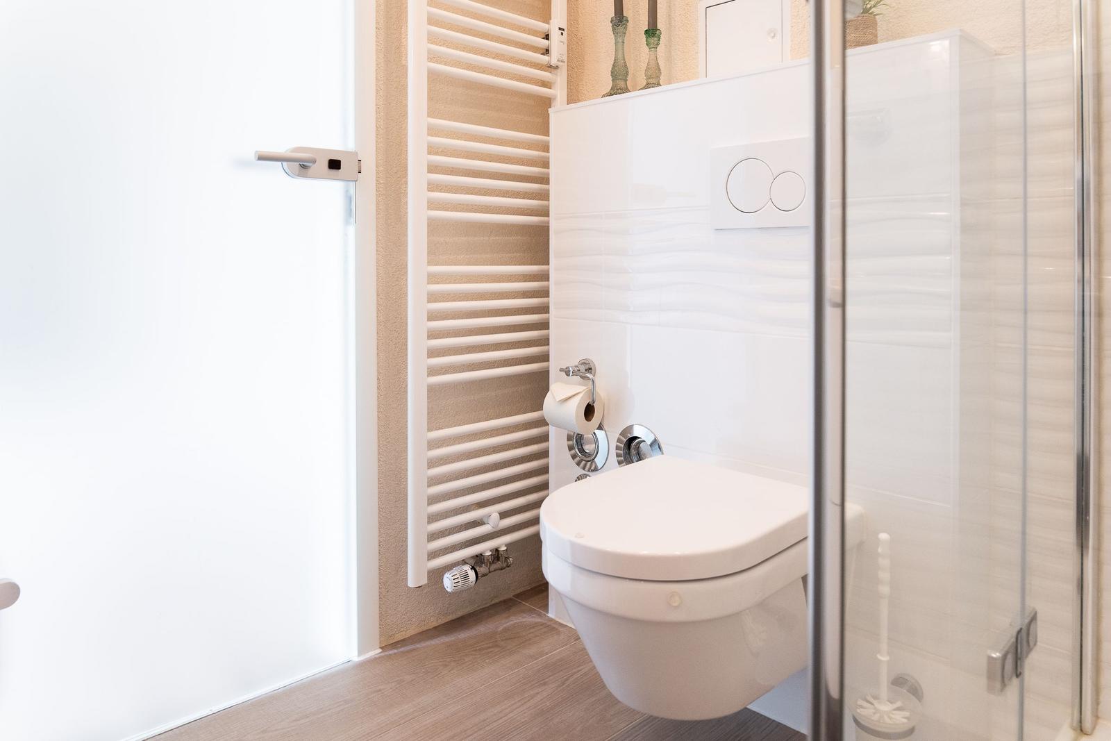 Toilette mit Dusche und Heizkörper an der Wand