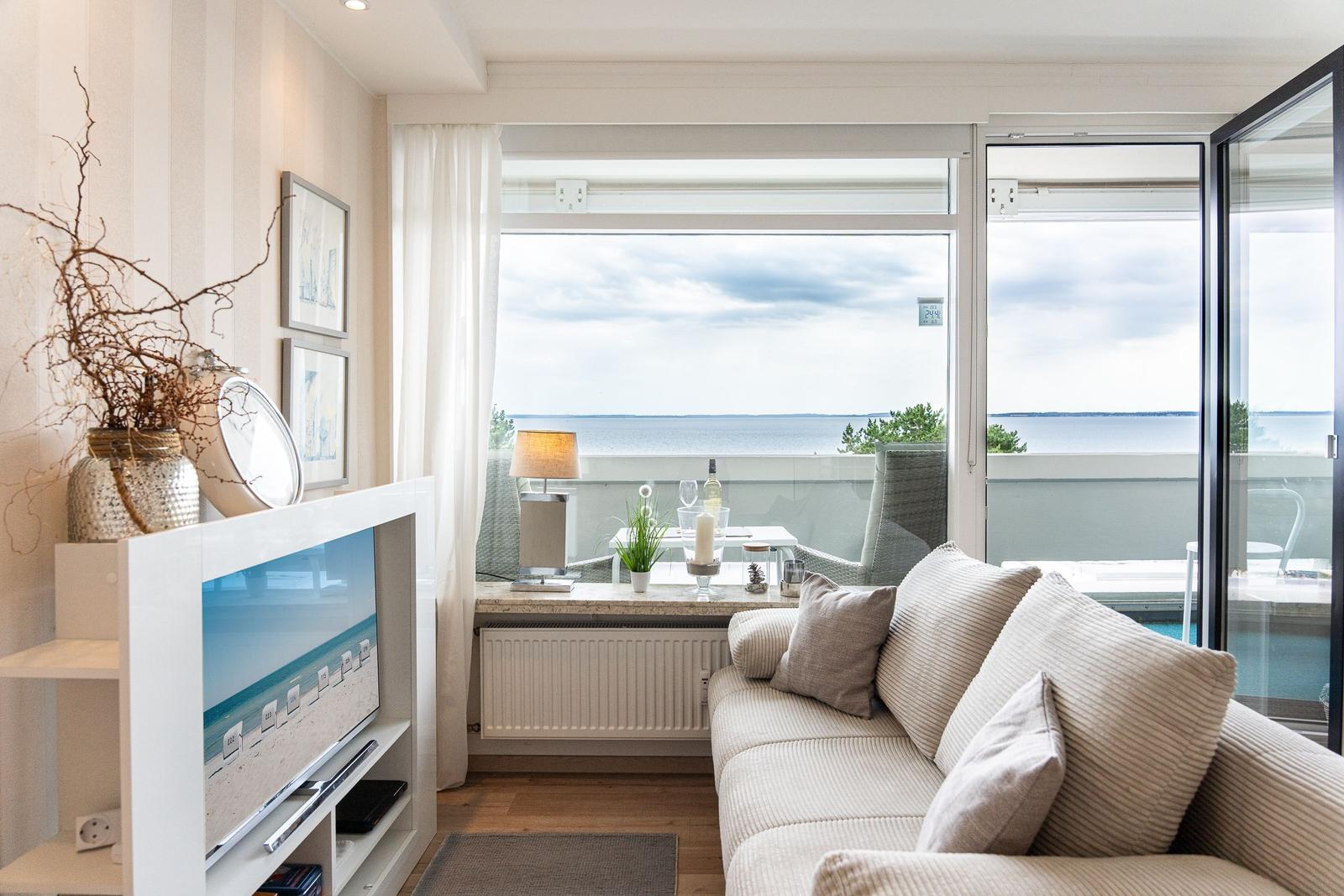 Wohnzimmer mit Sofa, TV und Balkonblick auf Wasser