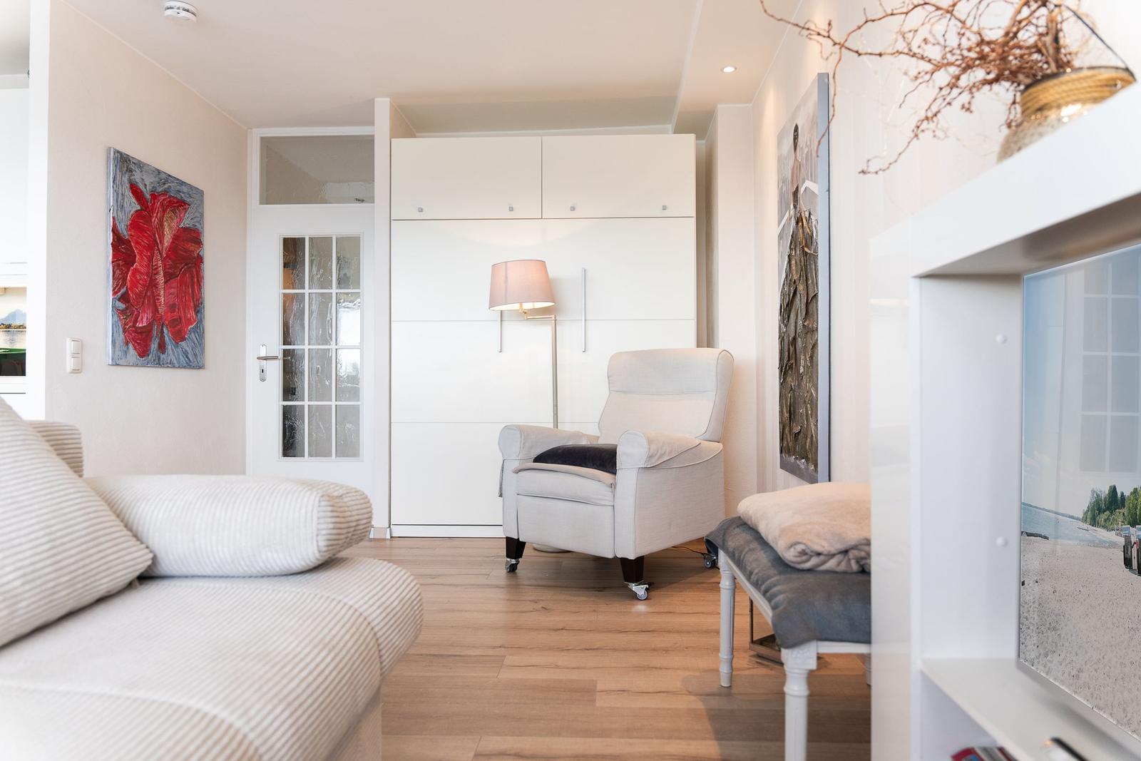 Wohnbereich mit Sitzgelegenheiten, Wandbildern und Holzboden.