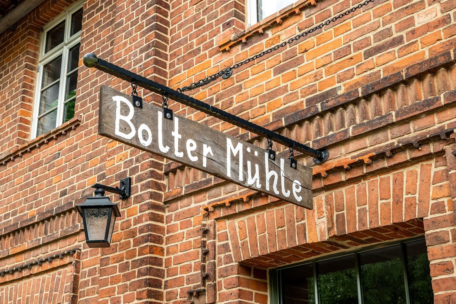 Holzschild mit der Aufschrift Bolter Mühle hängt an einer Backsteinwand.
