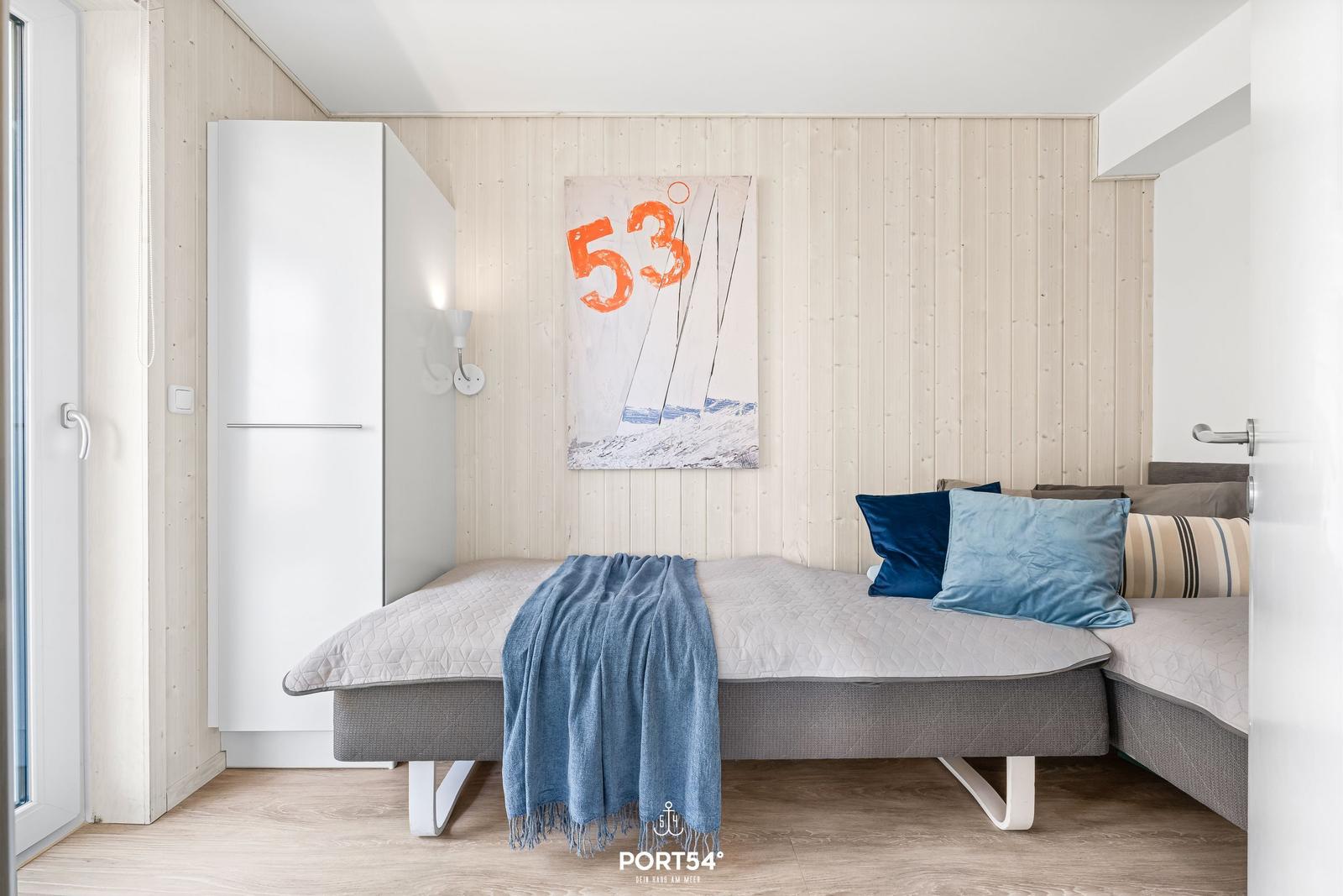 Schlafzimmer mit Bett, Kleiderschrank und Wandbild.