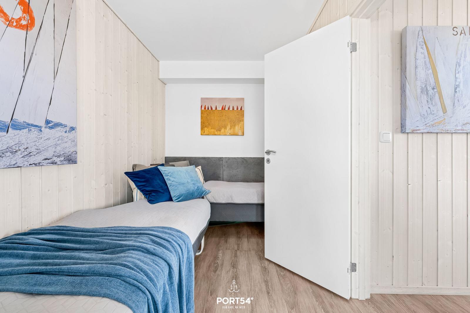 Schlafzimmer mit Bett, Wandbildern und Holzverkleidung.