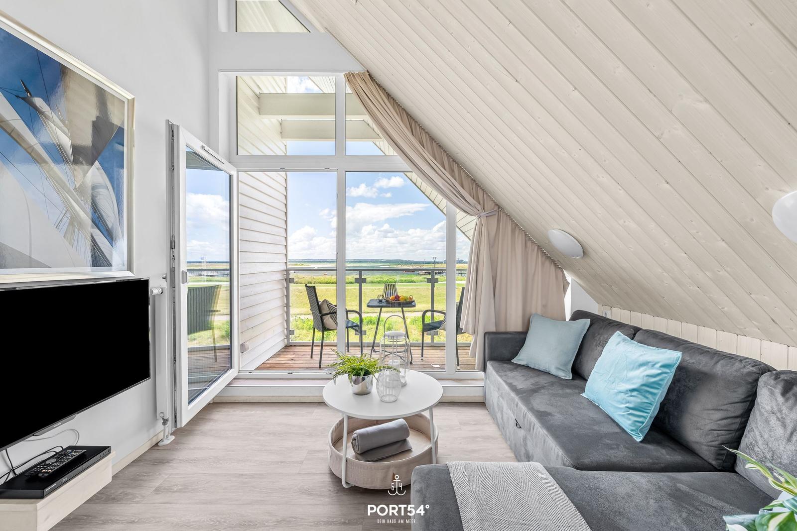 Wohnzimmer mit Sofa, TV und Balkon mit Meerblick.