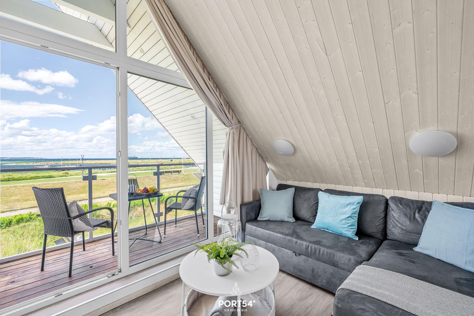 Wohnbereich mit Sofa, Tisch und Balkonblick aufs Meer.