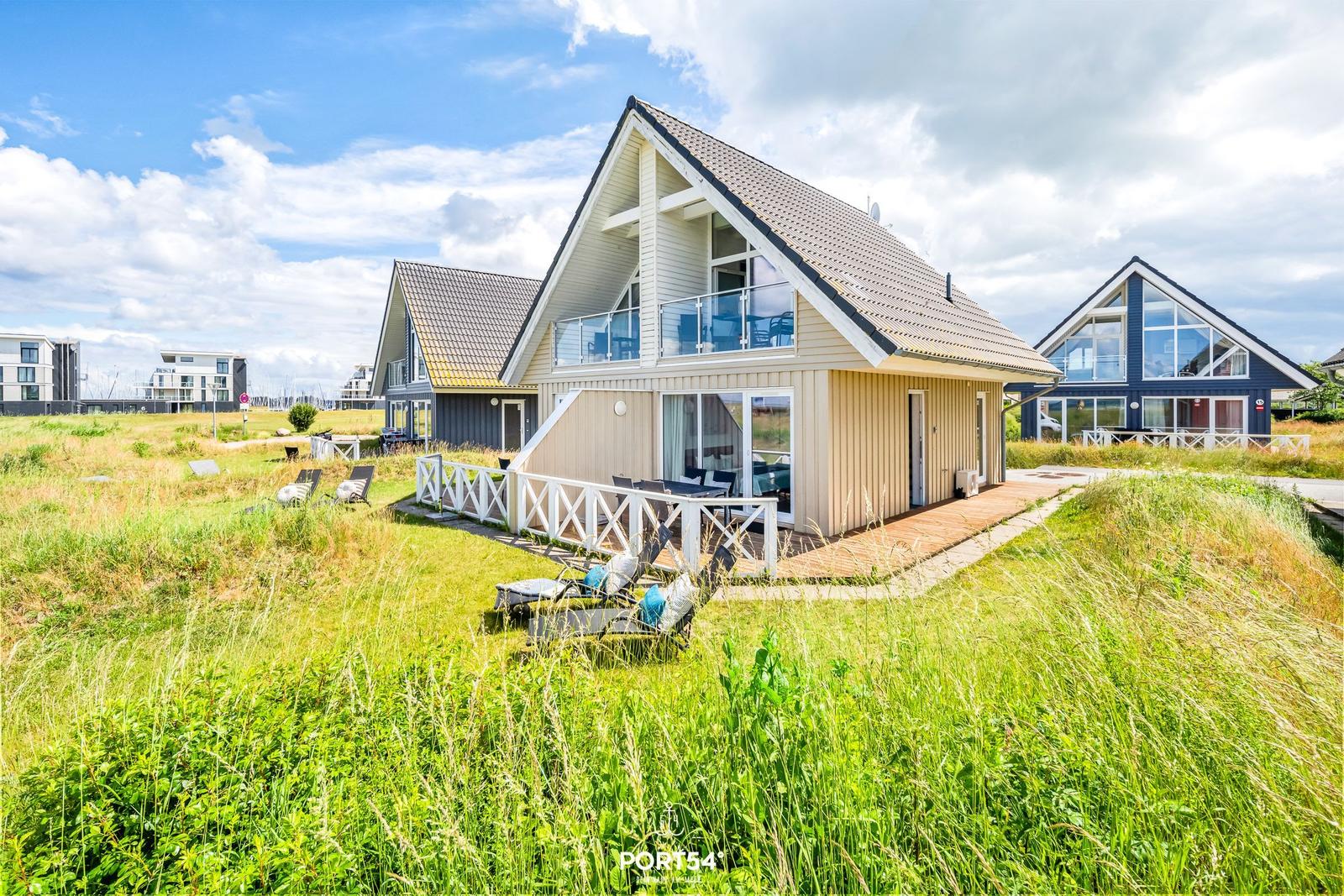 Moderne Strandhäuser mit Terrassen und Garten. Blick auf mehrere Häuser in Grünland.