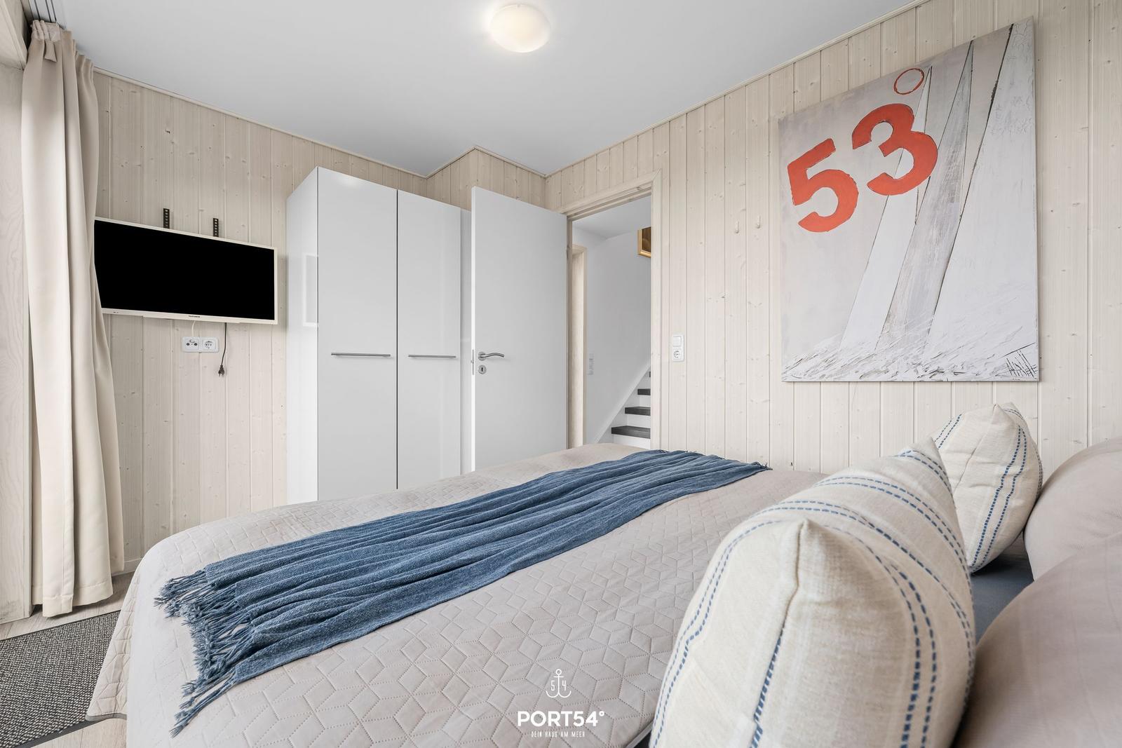 Schlafzimmer mit Bett, Kleiderschrank und Wandbild mit Zahlen