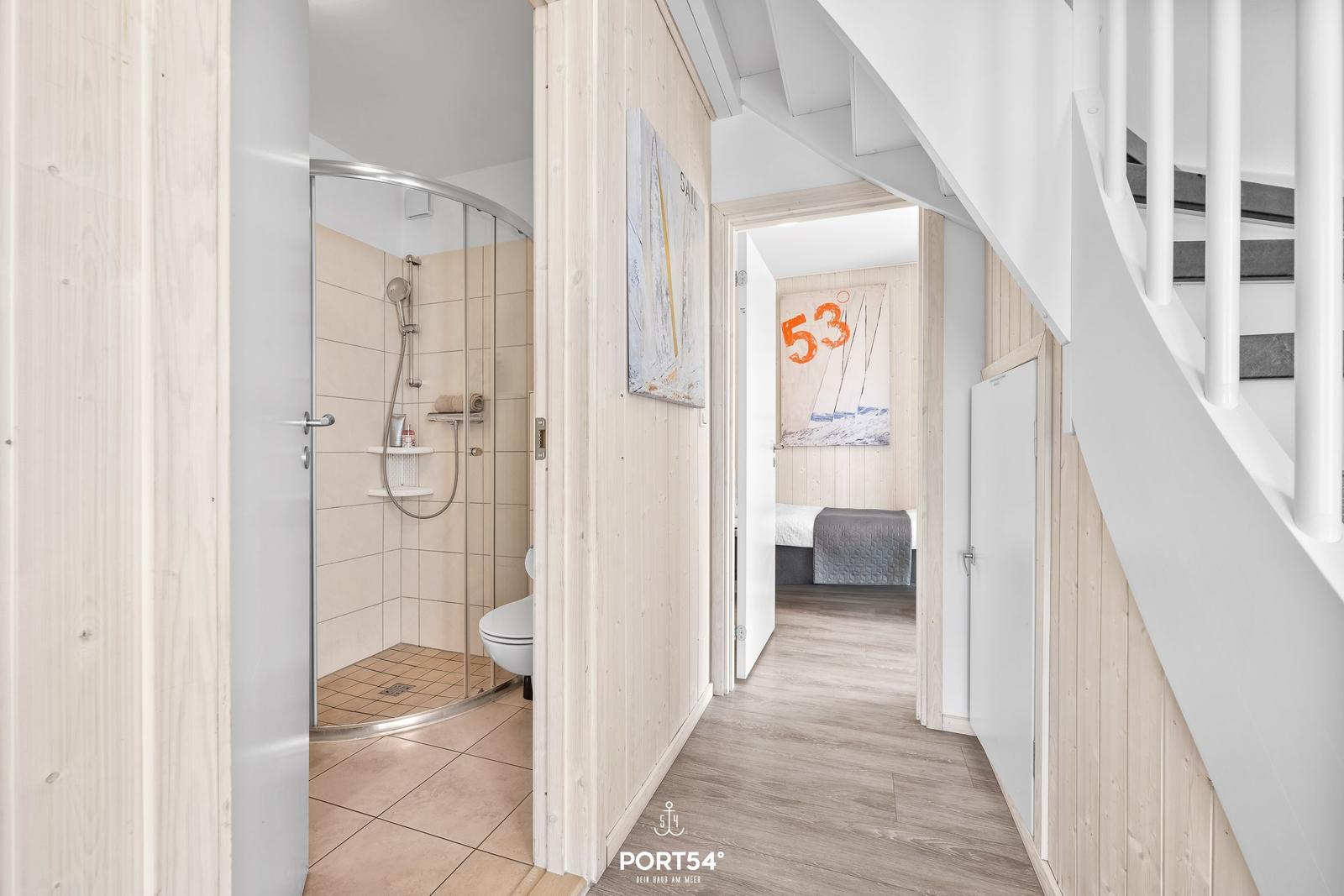 Flur mit Bad und Schlafzimmer, hölzerner Boden, weiße Treppe, Segelbild an der Wand.