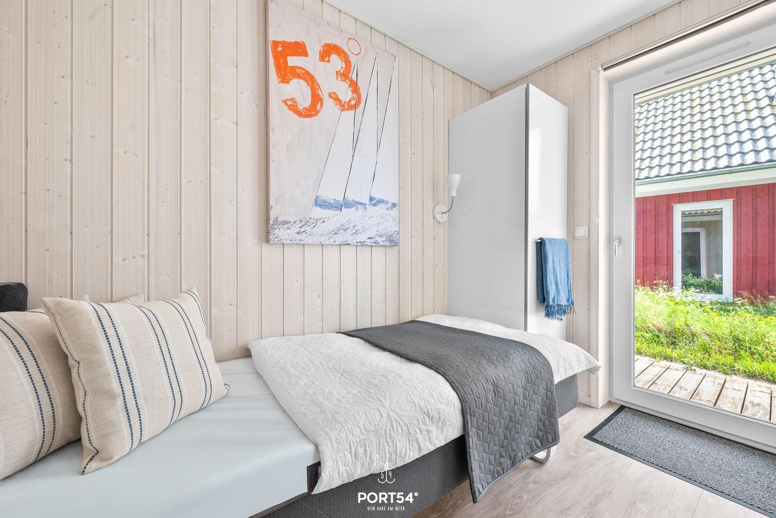Schlafzimmer mit Bett, Wandbild und Tür zum Garten.