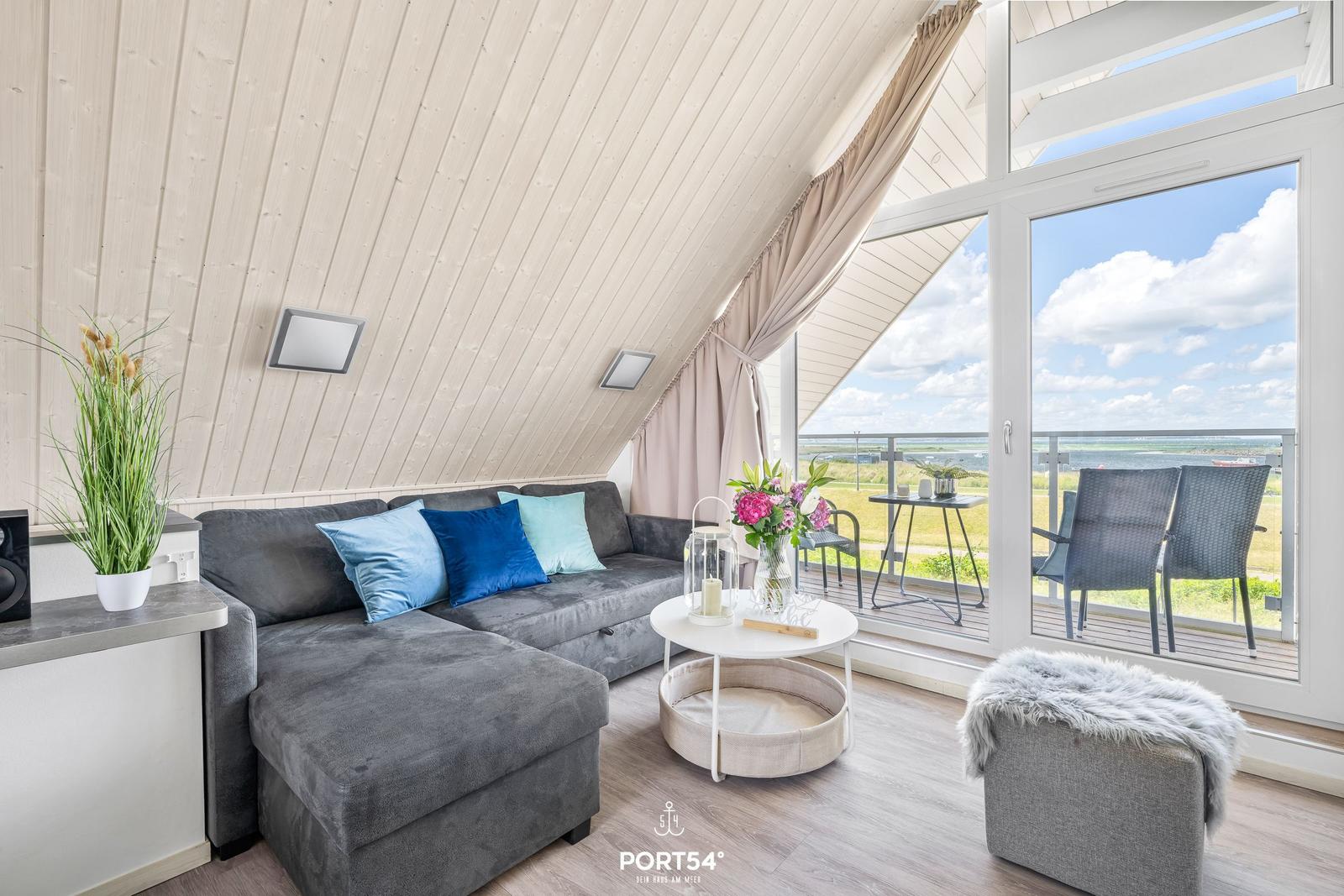 Wohnbereich mit Sofa, Tisch und Balkon mit Sicht auf Landschaft.