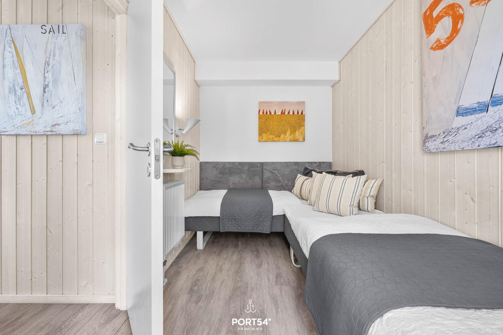 Zimmer mit zwei Betten, Holzwandverkleidung und Wandbildern.