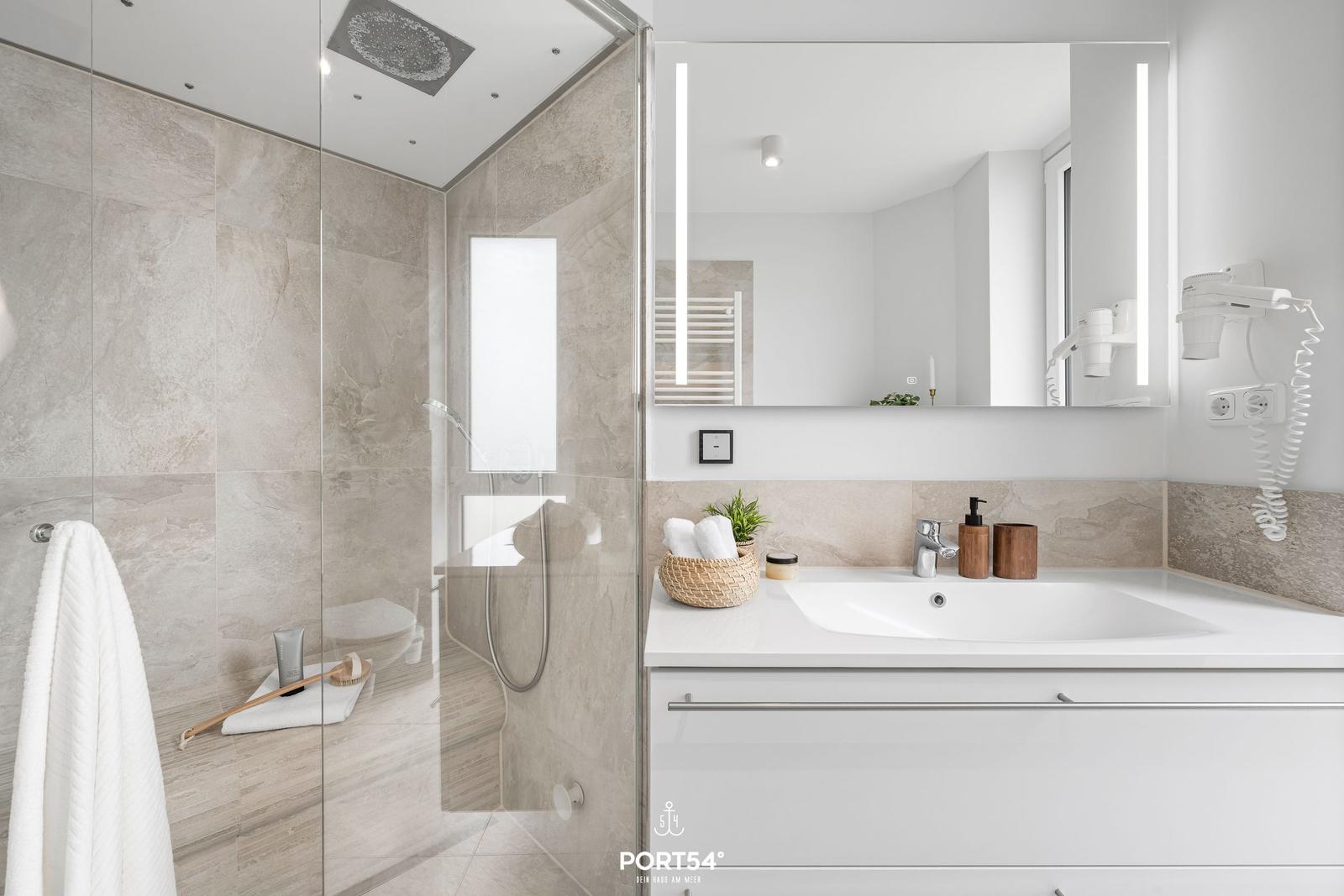 Moderne Badewanne mit Dusche und Spiegelschrank. Weiße Fliesen und Holzakzente.