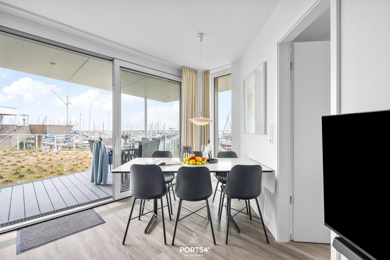 Essbereich mit Tisch und Stühlen, Blick auf Hafen und Terrasse.