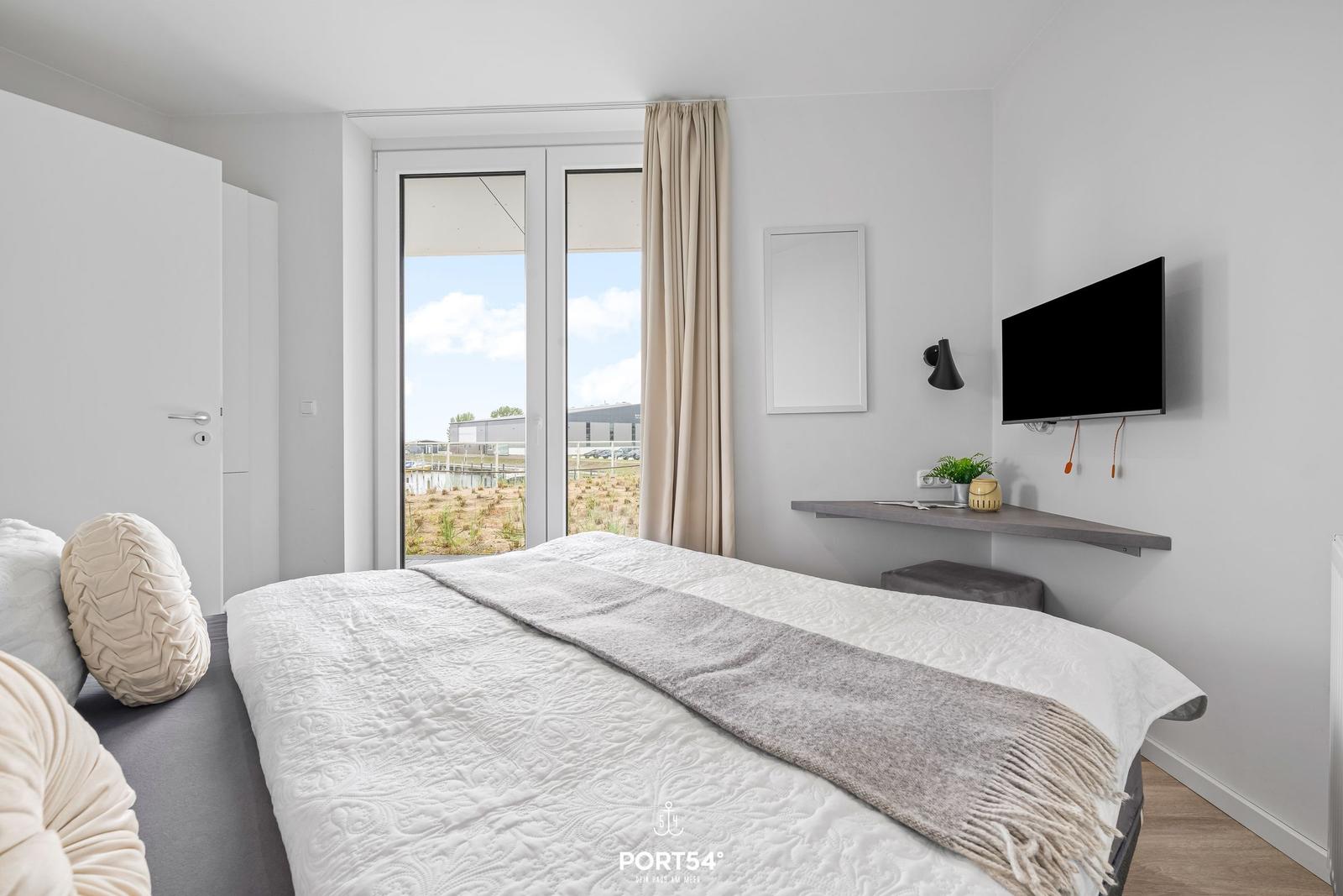 Schlafzimmer mit Bett, TV und Fenster zur Aussicht.