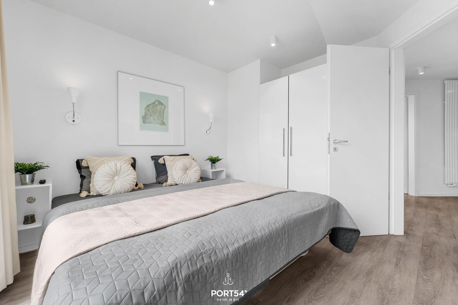 Schlafzimmer mit Bett, Kleiderschrank und Wandbild.
