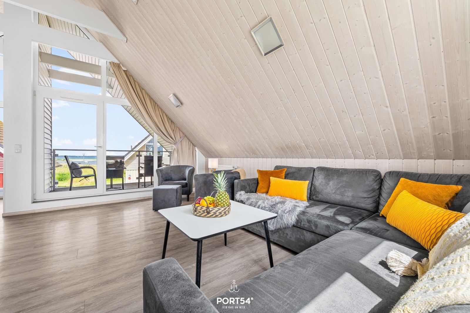 Wohnzimmer mit grauem Sofa, gelben Kissen und Blick auf Balkon