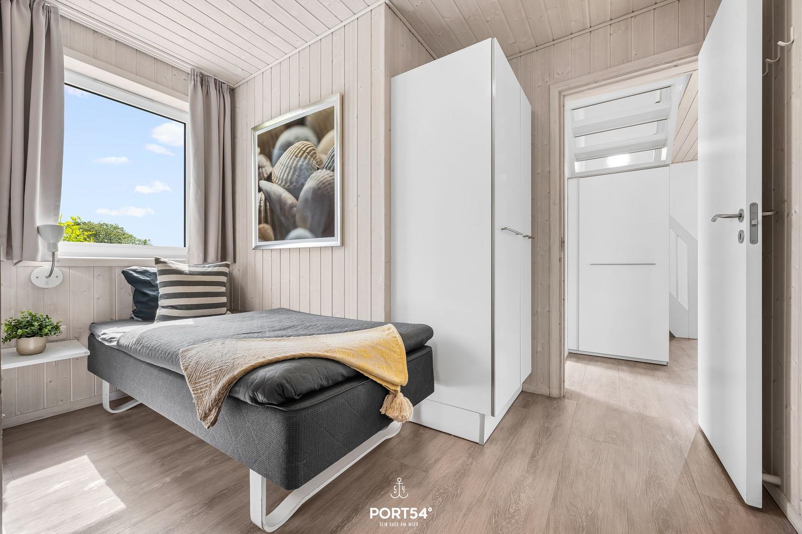 Schlafzimmer mit Bett, Kleiderschrank und Fenster mit Blick.