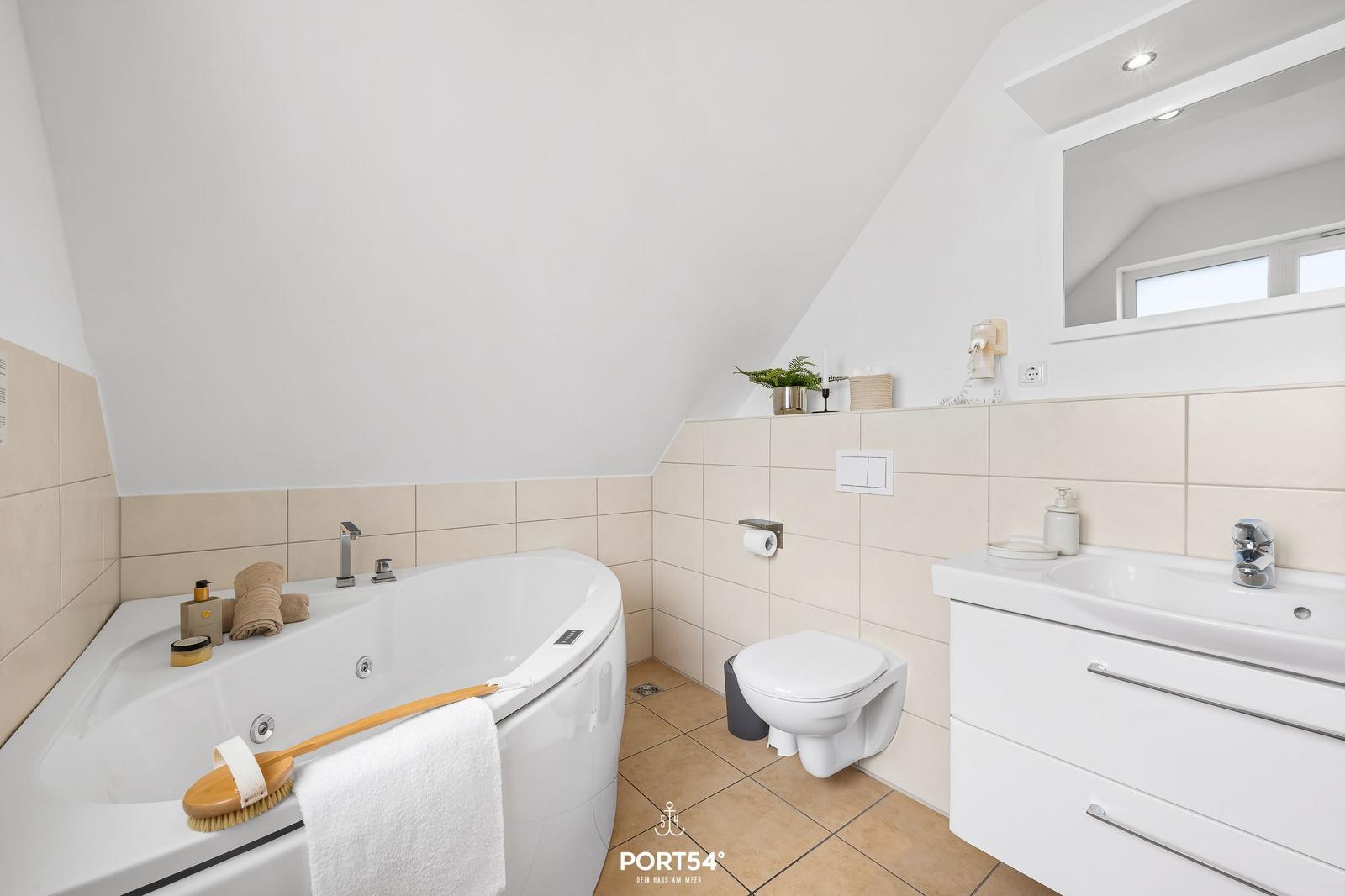Badezimmer mit Badewanne, Waschbecken und Toilette unter schrägem Dach