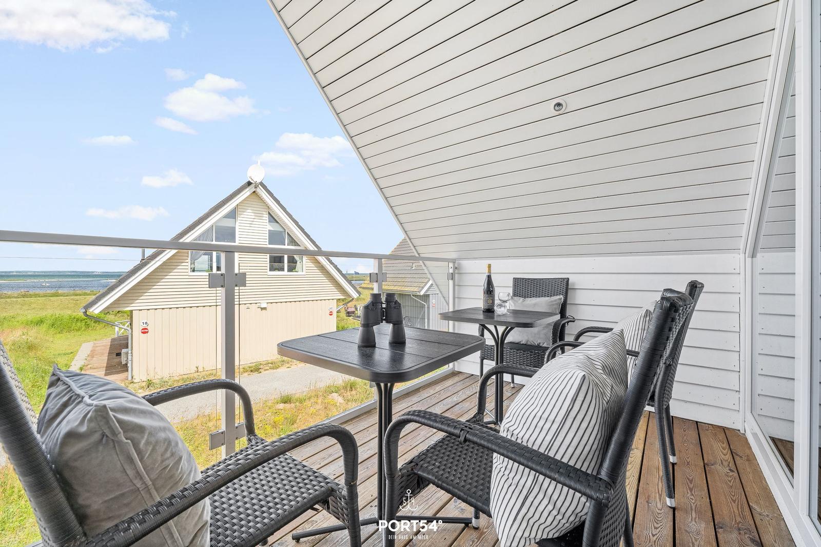 Terrasse mit Tisch, Stühlen und Blick auf Haus und Landschaft.