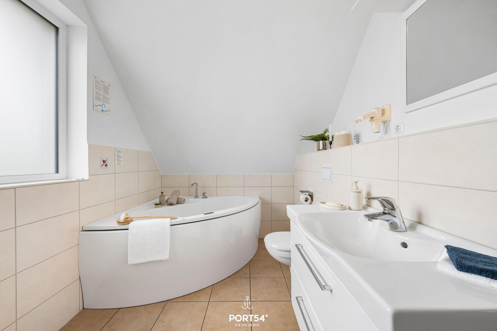 Dusche mit Badewanne, Waschbecken und Toilette in einem hellen Badezimmer.