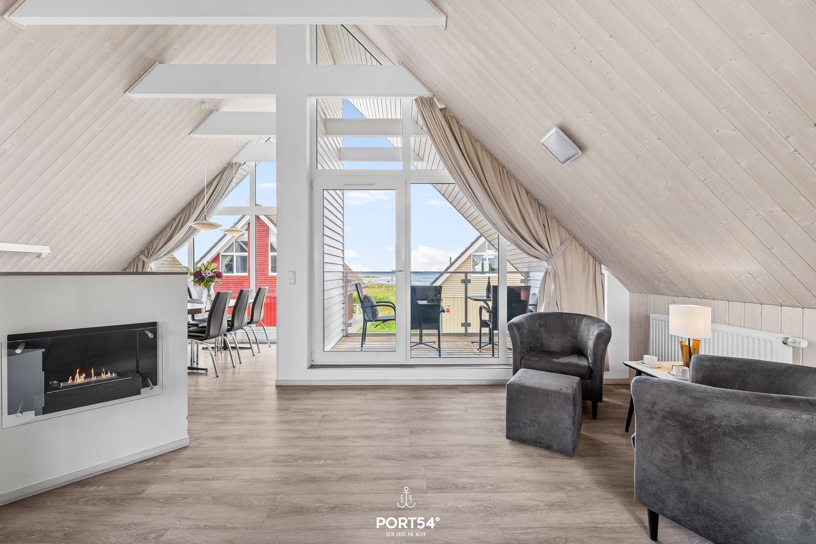 Wohnbereich mit Kamin, Sitzgelegenheiten und Blick auf Terrasse und Meer.